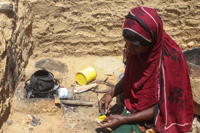 An internally displaced Yemeni woman starts a fire underneath a teapot at a makeshift camp for the internally displaced who fled their homes due to renewed clashes between Yemen's Saudi-backed government forces and the Houthi authorities in the northern Hajjah governorate on October 7, 2026. More than 200,000 people have been displaced in Yemen since fighting resumed between the Houthis and the Saudi-backed internationally recognised government, a UN agency said on October 7. (Photo by Essa AHMED / AFP)