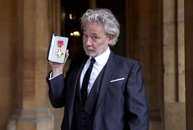 English film director and actor Dexter Fletcher poses with their medal after being appointed an Officer of the Order of the British Empire (OBE) at an investiture ceremony at Windsor Castle, in Windsor, west of London on October 7, 2026. (Photo by Andrew Matthews / POOL / AFP)