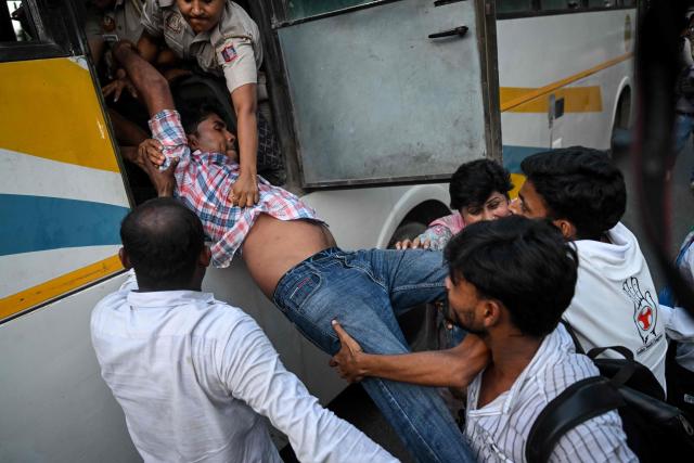 Security personnel try to detain a demonstrator as he jumps out of a bus during a protest by the opposition alliance INDIA bloc (Indian National Developmental Inclusive Alliance) in New Delhi on October 7, 2026 against the country's Chief Election Commissioner Gyanesh Kumar, calling for his resignation over alleged irregularities in the Special Intensive Revision (SIR) of electoral rolls. (Photo by Arun SANKAR / AFP)