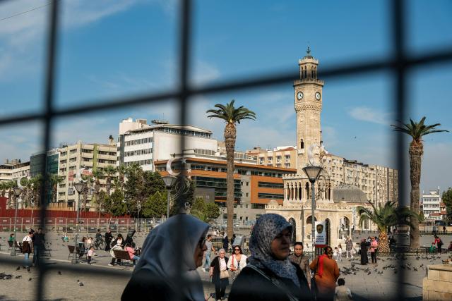 Pedestrians walk past police fences as Turkish Police block Konak square due to potential protests after Izmir mayor joined the ruling Justice and Development Party (AKP) in Izmir, on October 7, 2026. The mayor of Izmir, Turkey's third city and an opposition stronghold, on Wednesday defected to the ruling AKP, in a huge symbolic victory for Turkish President Recep Tayyip Erdogan. Mayor Cemil Tugay's decision to join the Islamic-rooted Justice and Development Party (AKP) was announced by Erdogan at a parliamentary group meeting in Ankara where he personally welcomed the mayor in a party-like atmosphere broadcast live on TV. (Photo by Murat Kocabas / AFP)