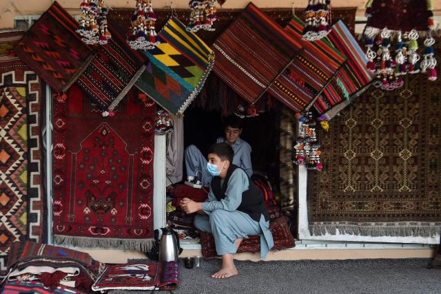 Afghan boys selling carpets wait for customers at a shop in Mazar-i-Sharif on October 7, 2026. (Photo by Atif ARYAN / AFP)