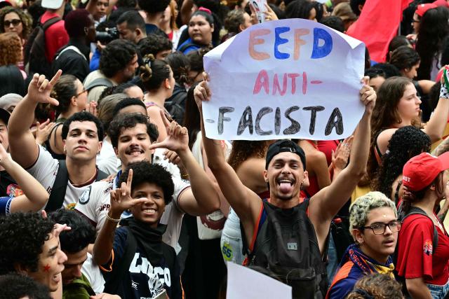 Students backing Brazil's President and presidential candidate Luiz Inacio Lula da Silva for the runoff election gesture and hold allusive signs during a march against the far right, in Rio de Janeiro, Brazil on October 7, 2026. Lula da Silva, who has risen from the political ashes several times, is heading to a runoff election against right-wing senator Flavio Bolsonaro on October 25, after a shock second-place finish in the first-round vote. (Photo by Pablo PORCIUNCULA / AFP)
