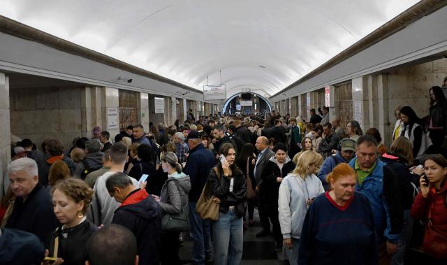 Passengers wait in a metro station during an air raid alert as metro trains stopped crossing the Dnipro River by the bridge to the left bank of Kyiv on October 7, 2026, amid the Russian invasion of Ukraine. (Photo by Sergei SUPINSKY / AFP)