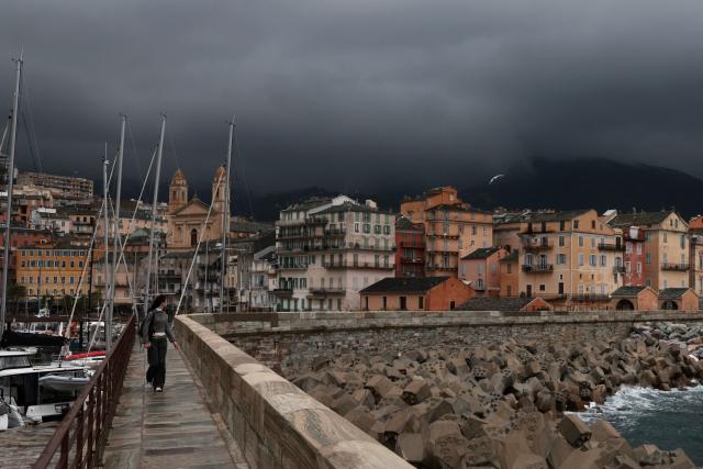 A woman walks in the rain at sunrise in the port of Bastia, on the French Mediterranean island of Corsica, on October 6, 2026. (Photo by Pascal POCHARD-CASABIANCA / AFP)