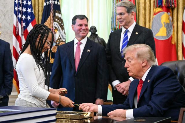 US President Donald Trump gives a pen to a child during an event about "Trump accounts," investment savings accounts for children, in the Oval Office in the White House in Washington, DC on October 7, 2026. (Photo by Alex WROBLEWSKI / AFP)
