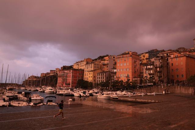 A man runs in the rain at sunrise in the port of Bastia, on the French Mediterranean island of Corsica, on October 6, 2026. (Photo by Pascal POCHARD-CASABIANCA / AFP)