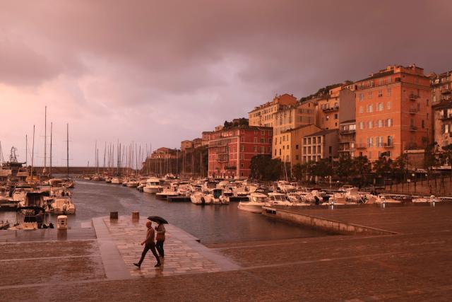 People walk in the rain at sunrise in the port of Bastia, on the French Mediterranean island of Corsica, on October 6, 2026. (Photo by Pascal POCHARD-CASABIANCA / AFP)
