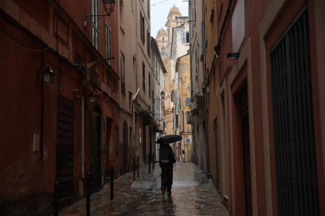 A woman walks in the rain at a norrow alley of the port of Bastia, on the French Mediterranean island of Corsica, on October 6, 2026. (Photo by Pascal POCHARD-CASABIANCA / AFP)