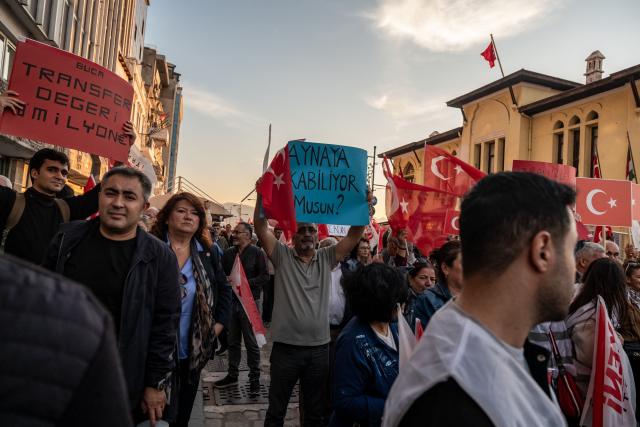 A protester holds a placard that reads "Can you look in the mirror?" during a demonstration to protest against Izmir mayor Cemil Tugay's defection to the ruling AKP party, in Izmir on October 7, 2026. More than 1,000 protesters gathered in Turkish opposition stronghold Izmir on Ocotber 6, 2026, angered by the defection of the city's mayor to President Recep Tayyip Erdogan's ruling AKP. The move was a huge symbolic victory for the Turkish leader, who has long wanted to control the secular resort city of 4.5 million people on Turkey's Aegean coast which has been held by the opposition for nearly 30 years. (Photo by Murat Kocabas / AFP)
