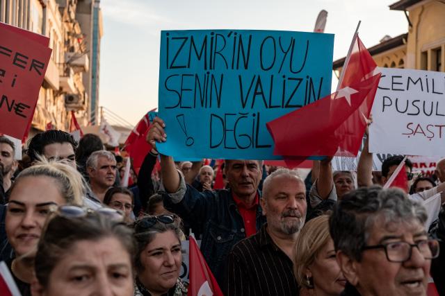 A protester holds a placard that reads "Vote is not your suitcase" while others chant slogans against the goverment during a demonstration against Izmir mayor Cemil Tugay's defection to the ruling AKP party, in Izmir on October 7, 2026. More than 1,000 protesters gathered in Turkish opposition stronghold Izmir on Ocotber 6, 2026, angered by the defection of the city's mayor to President Recep Tayyip Erdogan's ruling AKP. The move was a huge symbolic victory for the Turkish leader, who has long wanted to control the secular resort city of 4.5 million people on Turkey's Aegean coast which has been held by the opposition for nearly 30 years. (Photo by Murat Kocabas / AFP)