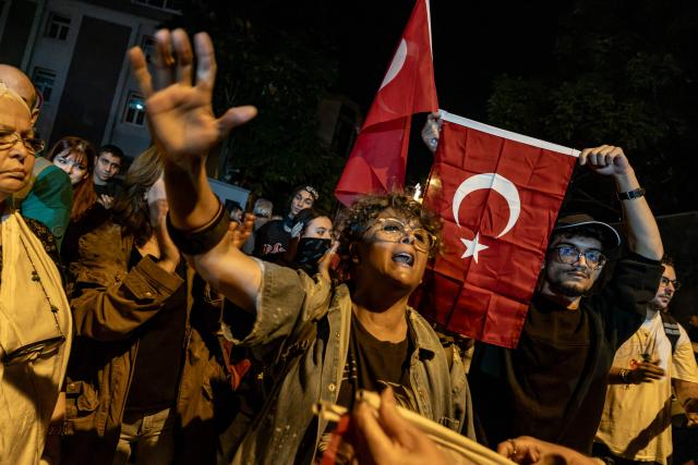 A protester holds a Turkish national flag while others chant slogans during a demonstration against Izmir mayor Cemil Tugay's defection to the ruling AKP party, in Izmir on October 7, 2026. More than 1,000 protesters gathered in Turkish opposition stronghold Izmir on October 7, 2026, angered by the defection of the city's mayor to President Recep Tayyip Erdogan's ruling AKP. The move was a huge symbolic victory for the Turkish leader, who has long wanted to control the secular resort city of 4.5 million people on Turkey's Aegean coast which has been held by the opposition for nearly 30 years. (Photo by Murat Kocabas / AFP)