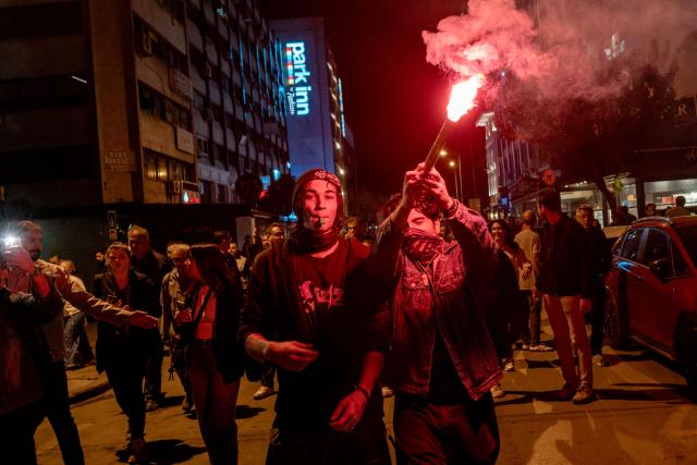 A protester holds a smoke flare while others chant slogans during a demonstration against Izmir mayor Cemil Tugay's defection to the ruling AKP party, in Izmir on October 7, 2026. More than 1,000 protesters gathered in Turkish opposition stronghold Izmir on October 7, 2026, angered by the defection of the city's mayor to President Recep Tayyip Erdogan's ruling AKP. The move was a huge symbolic victory for the Turkish leader, who has long wanted to control the secular resort city of 4.5 million people on Turkey's Aegean coast which has been held by the opposition for nearly 30 years. (Photo by Murat Kocabas / AFP)