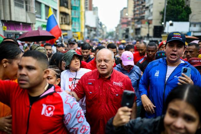 Venezuela's Minister of Interior, Justice and Peace Diosdado Cabello (C) takes part in a march marking the anniversary of late president Hugo Chavez's final electoral victory in 2012, in Caracas on October 7, 2026. (Photo by Maxwell BRICENO / AFP)