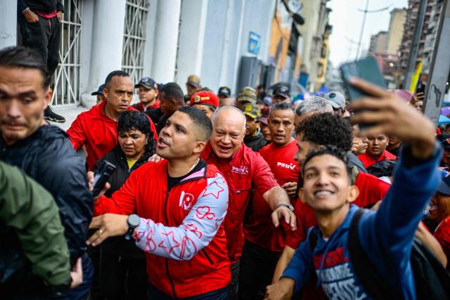 Venezuela's Minister of Interior, Justice and Peace Diosdado Cabello (C) takes part in a march marking the anniversary of late president Hugo Chavez's final electoral victory in 2012, in Caracas on October 7, 2026. (Photo by Maxwell BRICENO / AFP)