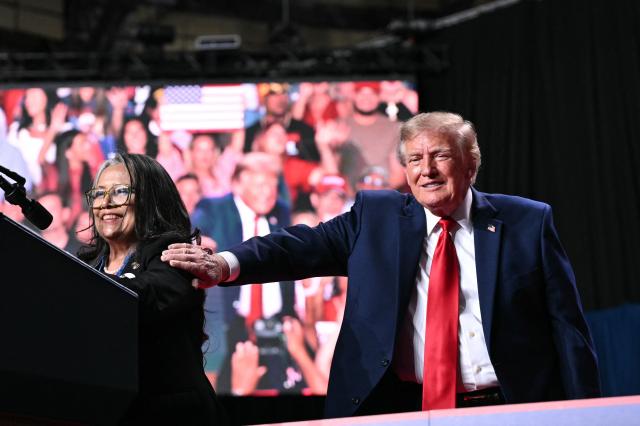 US President Donald Trump (R) with Marie Vega, mother of Javier Vega Jr, as she speaks during a campaign rally at the Freeman Coliseum in San Antonio, Texas, on October 7, 2026. Republican Senate candidate Ken Paxton is in a close race with Democratic candidate James Talarico for one of Texas' US Senate seats. (Photo by Mandel NGAN / AFP)