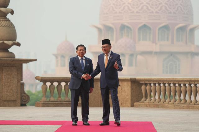 Myanmar’s President Min Aung Hlaing (L) shakes hands with Malaysia’s Prime Minister Anwar Ibrahim during a welcome ceremony at the prime minister’s office in Putrajaya on October 8, 2026. (Photo by Azneal Ishak / POOL / AFP)