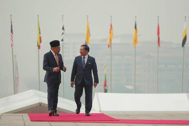 Myanmar’s President Min Aung Hlaing (R) walks with Malaysia’s Prime Minister Anwar Ibrahim during a welcome ceremony at the prime minister’s office in Putrajaya on October 8, 2026. (Photo by Azneal Ishak / POOL / AFP)