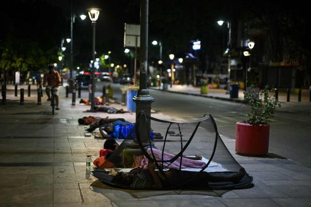People sleep on a footpath in early morning in Chennai on October 8, 2026. (Photo by R. Satish BABU / AFP)