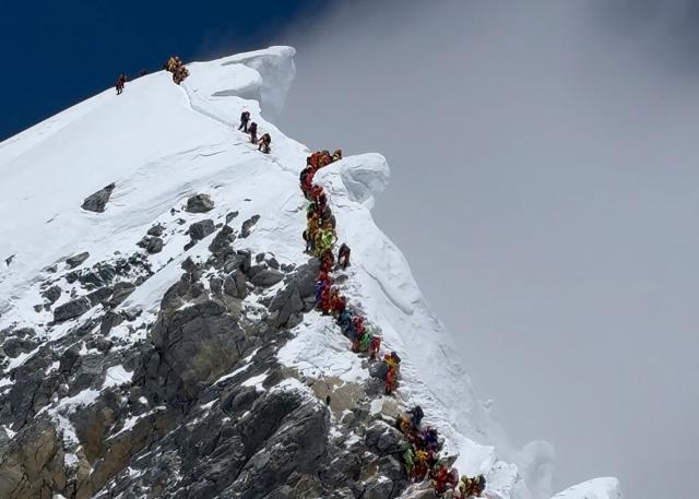 (FILES) This photograph taken on May 20, 2026 shows mountaineers climbing a slope lined up during their ascent from the Hillary Step to summit Mount Everest in Nepal. As a new biopic puts the life of mountaineer Tenzing Norgay Sherpa on screen, his son says climate change is transforming the Himalayas and making mountaineering increasingly dangerous. (Photo by Furte Sherpa / AFP)