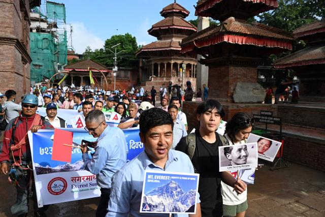 (FILES) Nepali people take part in a procession to mark the 18th International Everest Day and the 72nd anniversary of the first ascent of Mount Everest in Kathmandu on May 29, 2025. As a new biopic puts the life of mountaineer Tenzing Norgay Sherpa on screen, his son says climate change is transforming the Himalayas and making mountaineering increasingly dangerous. (Photo by PRAKASH MATHEMA / AFP)