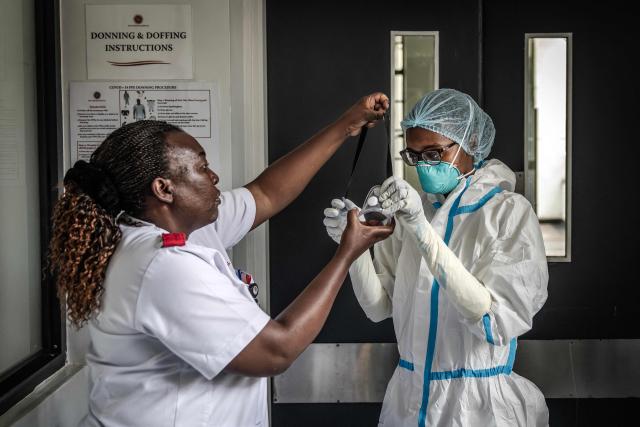 A nurse is assisted by a colleague in donning personal protective equipment (PPE) at an isolation facility prepared to receive potential Ebola patients during a media visit to Nairobi Hospital in Nairobi on October 7, 2026. Kenya has reported its first-ever Ebola death, the health minister announced on October 6, 2026, after a Kenyan man who had been living in the Democratic Republic of Congo died after returning to the country. (Photo by Luis TATO / AFP)