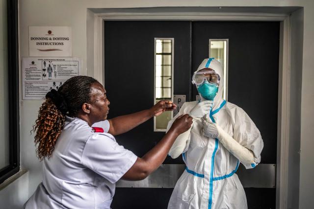 A nurse is assisted by a colleague in donning personal protective equipment (PPE) at an isolation facility prepared to receive potential Ebola patients during a media visit to Nairobi Hospital in Nairobi on October 7, 2026. Kenya has reported its first-ever Ebola death, the health minister announced on October 6, 2026, after a Kenyan man who had been living in the Democratic Republic of Congo died after returning to the country. (Photo by Luis TATO / AFP)