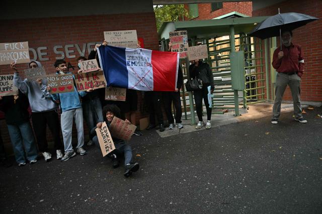 High-school students protesters pose with their placards and a French national flag during a blockade of high-school Deodat de Severac in Toulouse, on October 8, 2026, as part of a nationwide protest movement over learning conditions. Since late September, pupils have barred the entrances to hundreds of schools, complaining of teacher absences, overloaded timetables, dilapidated classrooms and buildings ill-adapted to rising temperatures, among other grievances. (Photo by Lionel BONAVENTURE / AFP)