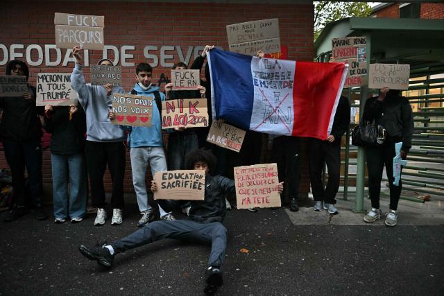 High-school students protesters pose with their placards and a French national flag during a blockade of high-school Deodat de Severac in Toulouse, on October 8, 2026, as part of a nationwide protest movement over learning conditions. Since late September, pupils have barred the entrances to hundreds of schools, complaining of teacher absences, overloaded timetables, dilapidated classrooms and buildings ill-adapted to rising temperatures, among other grievances. (Photo by Lionel BONAVENTURE / AFP)