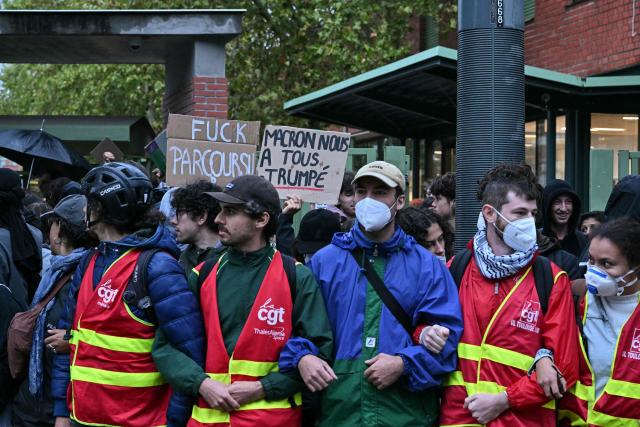 Members of French trade union General Confederation of Labour (CGT) stand with protesters during a blockade of high-school Deodat de Severac in Toulouse, on October 8, 2026, as part of a nationwide protest movement over learning conditions. Since late September, pupils have barred the entrances to hundreds of schools, complaining of teacher absences, overloaded timetables, dilapidated classrooms and buildings ill-adapted to rising temperatures, among other grievances. (Photo by Lionel BONAVENTURE / AFP)