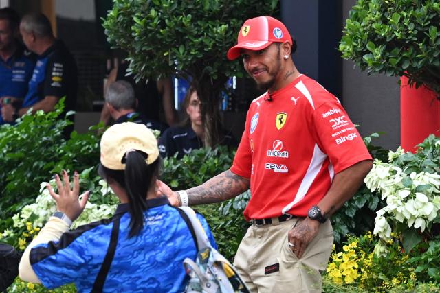 Ferrari's British driver Lewis Hamilton (R) smiles as he arrives at the paddock ahead of the Singapore Formula One Grand Prix night race in Singapore on October 8, 2026. (Photo by Roslan RAHMAN / AFP)