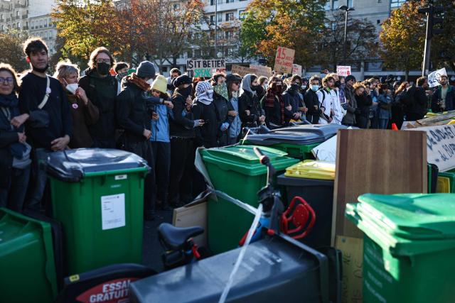 Adult protesters form a chain with their arms to protect teenagers on a blockade action near Helene Boucher high-school during a demonstration of high-school students in Paris, on October 8, 2026, as part of a nationwide protest movement over learning conditions. Since late September, pupils have barred the entrances to hundreds of schools, complaining of teacher absences, overloaded timetables, dilapidated classrooms and buildings ill-adapted to rising temperatures, among other grievances. (Photo by SIMON WOHLFAHRT / AFP)