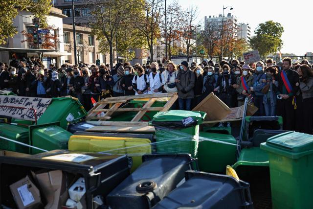 Adult protesters form a chain with their arms to protect teenagers on a blockade action near Helene Boucher high-school during a demonstration of high-school students in Paris, on October 8, 2026, as part of a nationwide protest movement over learning conditions. Since late September, pupils have barred the entrances to hundreds of schools, complaining of teacher absences, overloaded timetables, dilapidated classrooms and buildings ill-adapted to rising temperatures, among other grievances. (Photo by SIMON WOHLFAHRT / AFP)