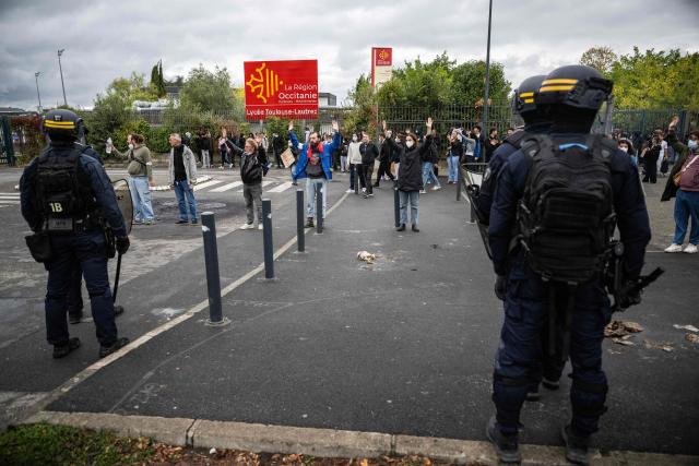 Adults, teachers, union members and parents, raise their arms to protect the students from riot police during a blockade of high-school Toulouse-Lautrec in Toulouse, on October 8, 2026, as part of a nationwide protest movement over learning conditions. Since late September, pupils have barred the entrances to hundreds of schools, complaining of teacher absences, overloaded timetables, dilapidated classrooms and buildings ill-adapted to rising temperatures, among other grievances. (Photo by Lionel BONAVENTURE / AFP)