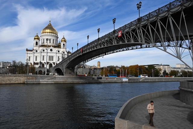 A pedestrian walks on an embankment with the Cathedral of Christ the Saviour in the background in central Moscow on October 8, 2026. (Photo by Igor IVANKO / AFP)