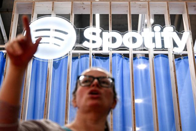 A visitor is seen below a Spotify logo at the 78th Frankfurt book fair, the world's biggest trade fair for books, in Frankfurt am Main, western Germany on October 8, 2026. From October 7 to 11, 2026, publishing experts will meet up with partners from the technology and creative industries such as film and games at one of the world’s leading venues for printed and digital content with the Czech republic as guest of honour. (Photo by Kirill KUDRYAVTSEV / AFP)