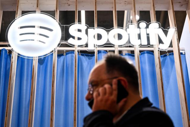 A visitor walks below a Spotify logo at the 78th Frankfurt book fair, the world's biggest trade fair for books, in Frankfurt am Main, western Germany on October 8, 2026. From October 7 to 11, 2026, publishing experts will meet up with partners from the technology and creative industries such as film and games at one of the world’s leading venues for printed and digital content with the Czech republic as guest of honour. (Photo by Kirill KUDRYAVTSEV / AFP)