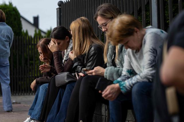 Local residents wait next to the scene where a 15-year-old fatally stabbed the caretaker of his former school and wounded two other adults at the John-Paul II primary school in Leszczydol-Nowiny, Poland, on October 8, 2026, a day after a similar knife attack wounded nine in a Polish high school, police said. Police arrested the boy after the attack at the John-Paul II primary school in Leszczydol-Nowiny, a small town 70 kilometres (40 miles) northeast of Warsaw, a police spokesperson told AFP. (Photo by Wojtek RADWANSKI / AFP)