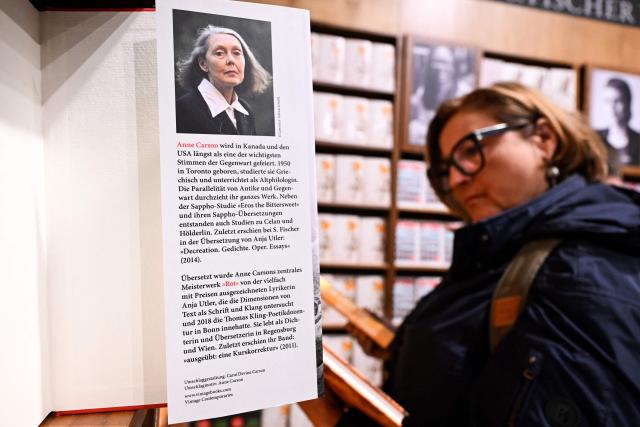 A reader looks at books of 2026 Nobel Prize in Literature laureate Canadian writer Anne Carson on display at the S. Fischer publishing house's booth at the 78th Frankfurt book fair, the world's biggest trade fair for books, in Frankfurt am Main, western Germany on October 8, 2026. From October 7 to 11, 2026, publishing experts will meet up with partners from the technology and creative industries such as film and games at one of the worlds leading venues for printed and digital content with the Czech republic as guest of honour. (Photo by Kirill KUDRYAVTSEV / AFP)