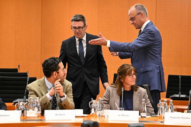 British Prime Minister Andy Burnham is shown to his seat by German Chancellor Friedrich Merz (R) as they arrive for a Business forum at the Chancellery in Berlin on October 8, 2026. (Photo by Tobias SCHWARZ / AFP)