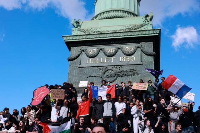 Protesters hold national flags on the July Column during a demonstration of high-school students at Place de la Bastille, in Paris, on October 8, 2026, as part of a nationwide protest movement over learning conditions. Since late September, pupils have barred the entrances to hundreds of schools, complaining of teacher absences, overloaded timetables, dilapidated classrooms and buildings ill-adapted to rising temperatures, among other grievances. (Photo by Kenzo TRIBOUILLARD / AFP)