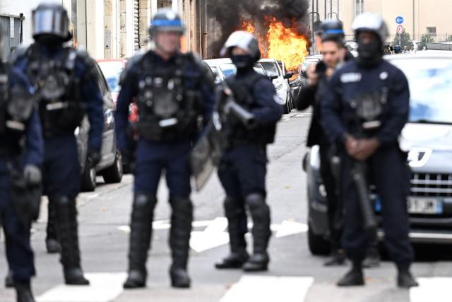French police officers face protesters as a car burns behind them during a student demonstration in Nancy, eastern France, on October 8, 2026, as part of a nationwide protest movement over learning conditions. Since late September, pupils have barred the entrances to hundreds of schools, complaining of teacher absences, overloaded timetables, dilapidated classrooms and buildings ill-adapted to rising temperatures, among other grievances. (Photo by Jean-Christophe VERHAEGEN / AFP)