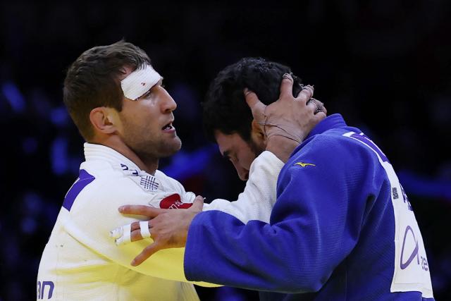 Serbia's Nemanja Majdov (white) and Azerbaijan's Murad Fatiyev embrace each other after the men's under 90 kg bronze medal bout at the World Judo Championships in Baku on October 8, 2026. (Photo by Anne-Christine POUJOULAT / AFP)