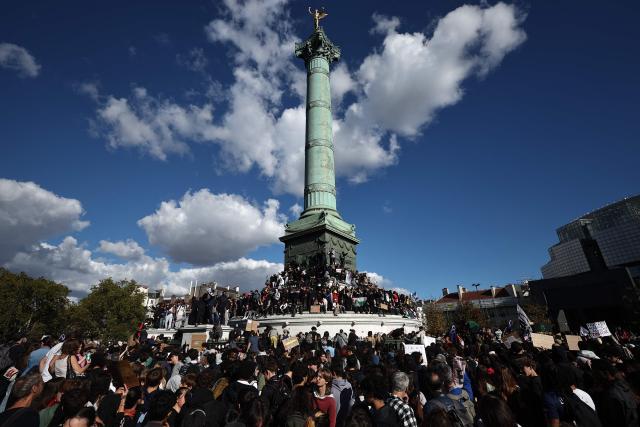 Youth climb the Column of July monument during a demonstration as part of a nationwide day of actions called by high-school students who for days have been demanding better learning conditions in protests punctuated by violent confrontations, in Paris on October 8, 2026. Since late September, pupils have barred the entrances to hundreds of schools, complaining of teacher absences, overloaded timetables, dilapidated classrooms and buildings ill-adapted to rising temperatures, among other grievances. (Photo by SIMON WOHLFAHRT / AFP)