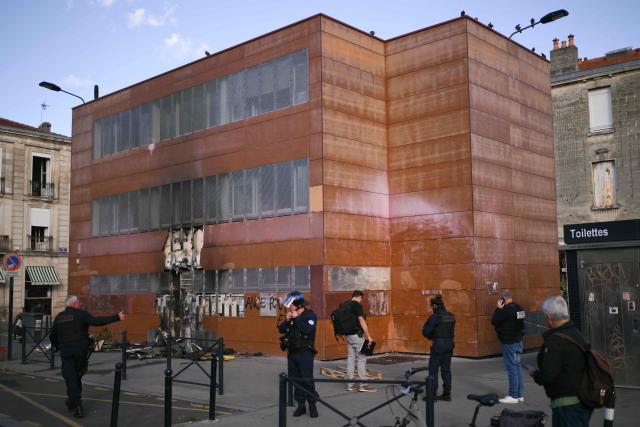Judicial police officers inspect the facade of the Capucins Market after it was set on fire by protesters during a high-school student demonstration in Bordeaux on October 8, 2026, as part of a nationwide movement over learning conditions. Since late September, pupils have barred the entrances to hundreds of schools, complaining of teacher absences, overloaded timetables, dilapidated classrooms and buildings ill-adapted to rising temperatures, among other grievances. (Photo by Christophe ARCHAMBAULT / AFP)