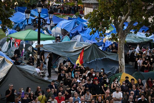 People at a housing rights activists' camp gather ahead of a demonstration called by far-right groups seeking the camp's eviction at City Hall Square in Valencia, eastern Spain, on October 8, 2026. (Photo by Jose JORDAN / AFP)