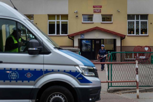 Police officers stand in front of the school where a 15-year-old fatally stabbed the caretaker of his former school and wounded two other adults at the John-Paul II primary school in Leszczydol-Nowiny, Poland, on October 8, 2026, a day after a similar knife attack wounded nine in a Polish high school, police said. Police arrested the boy after the attack at the John-Paul II primary school in Leszczydol-Nowiny, a small town 70 kilometres (40 miles) northeast of Warsaw, a police spokesperson told AFP. (Photo by Wojtek RADWANSKI / AFP)