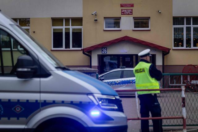 Police officers stand in front of the school where a 15-year-old fatally stabbed the caretaker of his former school and wounded two other adults at the John-Paul II primary school in Leszczydol-Nowiny, Poland, on October 8, 2026, a day after a similar knife attack wounded nine in a Polish high school, police said. Police arrested the boy after the attack at the John-Paul II primary school in Leszczydol-Nowiny, a small town 70 kilometres (40 miles) northeast of Warsaw, a police spokesperson told AFP. (Photo by Wojtek RADWANSKI / AFP)