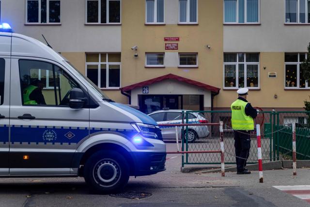 Police officers stand in front of the school where a 15-year-old fatally stabbed the caretaker of his former school and wounded two other adults at the John-Paul II primary school in Leszczydol-Nowiny, Poland, on October 8, 2026, a day after a similar knife attack wounded nine in a Polish high school, police said. Police arrested the boy after the attack at the John-Paul II primary school in Leszczydol-Nowiny, a small town 70 kilometres (40 miles) northeast of Warsaw, a police spokesperson told AFP. (Photo by Wojtek RADWANSKI / AFP)