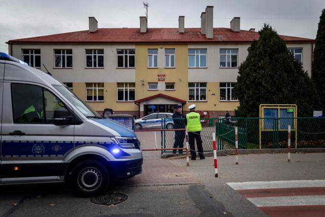 Police officers stand in front of the school where a 15-year-old fatally stabbed the caretaker of his former school and wounded two other adults at the John-Paul II primary school in Leszczydol-Nowiny, Poland, on October 8, 2026, a day after a similar knife attack wounded nine in a Polish high school, police said. Police arrested the boy after the attack at the John-Paul II primary school in Leszczydol-Nowiny, a small town 70 kilometres (40 miles) northeast of Warsaw, a police spokesperson told AFP. (Photo by Wojtek RADWANSKI / AFP)