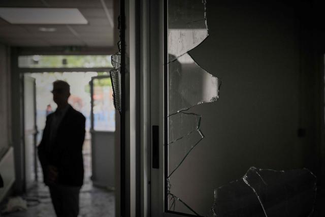 A man stands behind shattered windows in a corridor of the "Les Iris" high school in Lormont near Bordeaux, southwestern France, on October 8, 2026, after youths ransacked part of the school, stealing around ten computers and setting fire to a stockpile of paper, according to the headteacher. Since late September, pupils have barred the entrances to hundreds of schools, complaining of teacher absences, overloaded timetables, dilapidated classrooms and buildings ill-adapted to rising temperatures, among other grievances. (Photo by Philippe LOPEZ / AFP)
